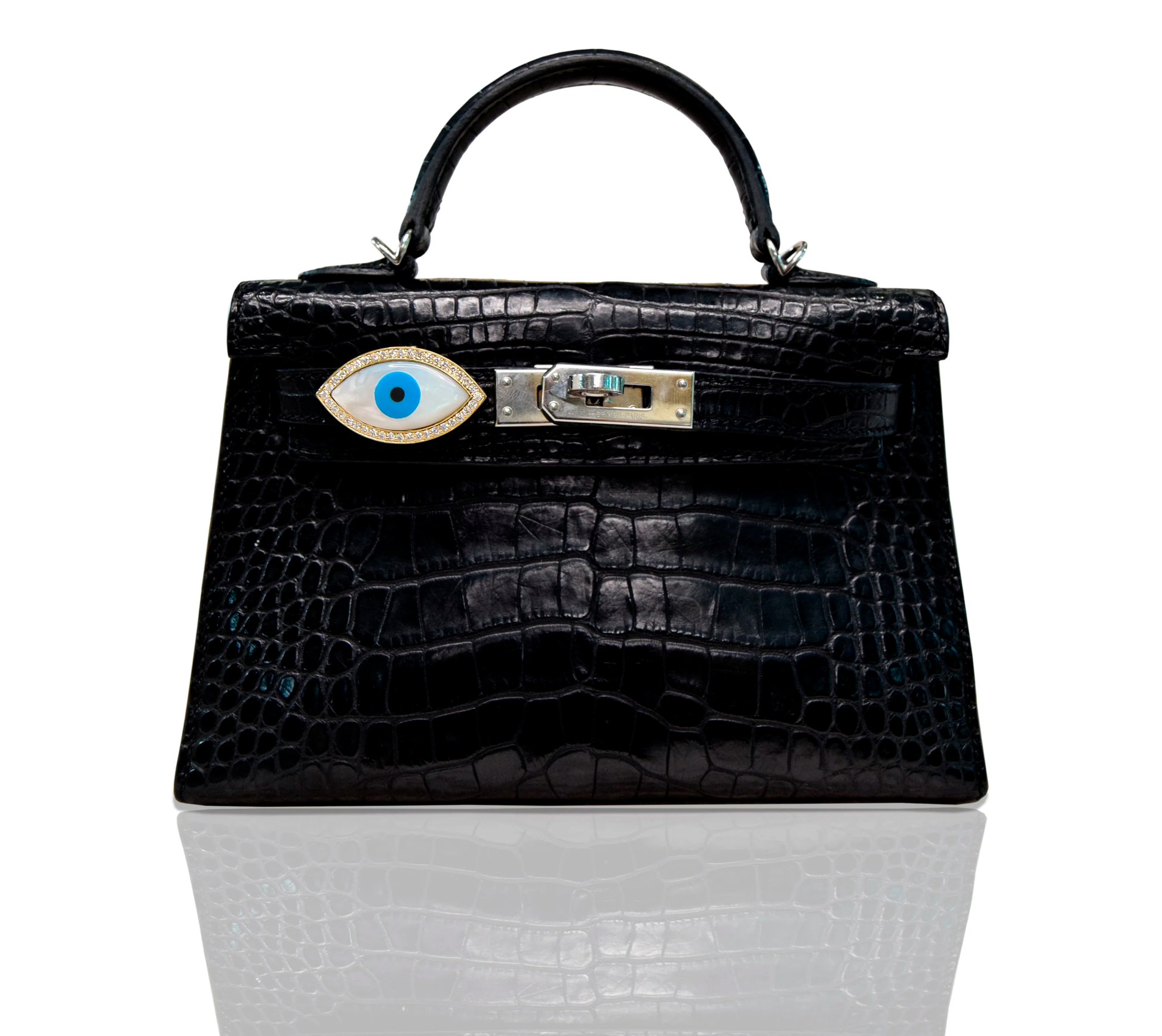 A black handbag with a marquise-shaped blue evil eye accessory affixed to it, set against a white background, collection-preview.