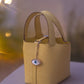 Yellow handbag with a decorative chain and evil eye charm 