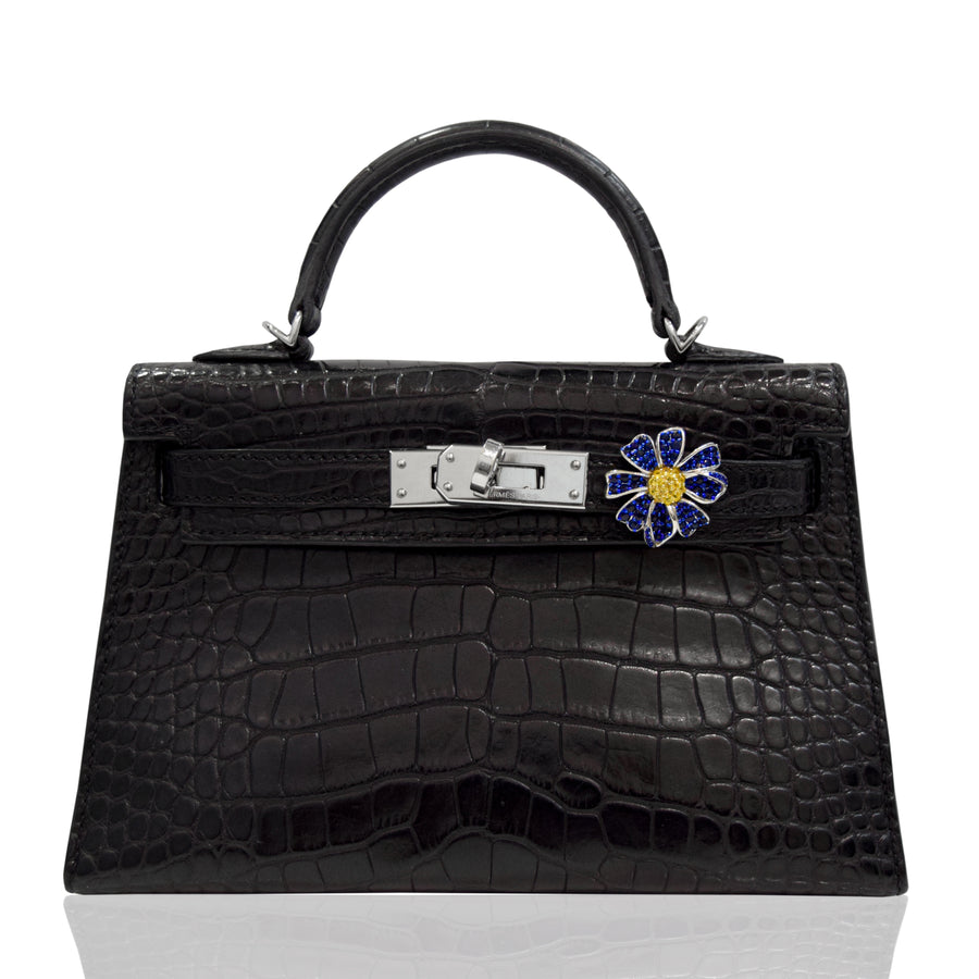 Black crocodile skin handbag with a decorative clasp on a white background, collection-preview