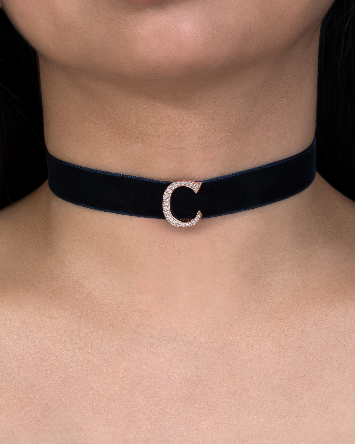 Navy blue velvet choker with a silver clasp on a person's neck against a black background