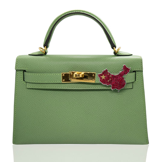 Green handbag with pink flower accessory on a white background, collection-preview