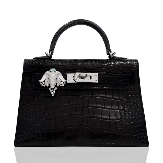 Black crocodile skin handbag with a decorative clasp on a white background, collection-preview