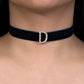 Black choker with a diamond 'D' clasp on a person's neck