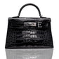 A black handbag with a crocodile pattern, featuring a metallic clasp and a leather handle, collection-preview.