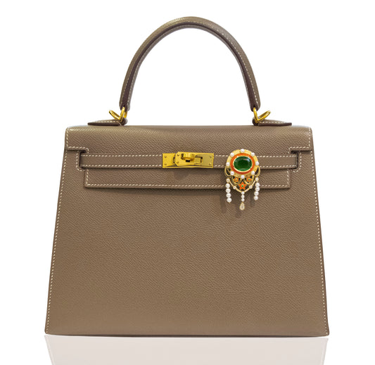 Brown handbag with decorative clasp on a white background, collection-preview