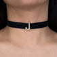 Black choker necklace with a gold 'J' pendant on a person's neck.