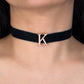 Navy blue velvet choker with a rose gold letter 'K' on a person's neck.
