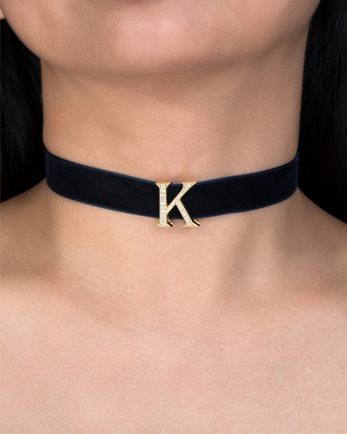 Navy velvet choker with gold letter 'K' on a person's neck
