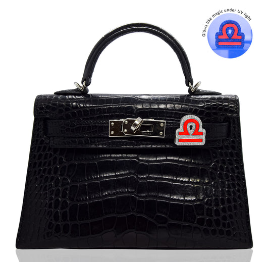 Black crocodile-patterned handbag with a distinctive clasp on a white background, collection-preview