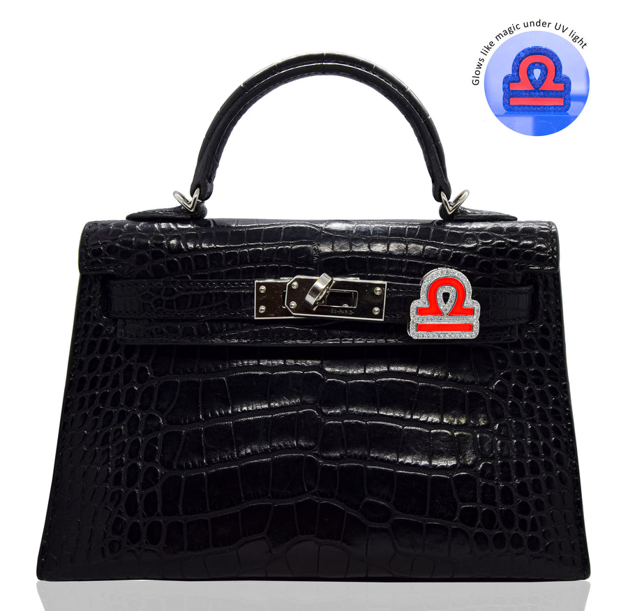 Black crocodile-patterned handbag with a distinctive clasp on a white background, collection-preview