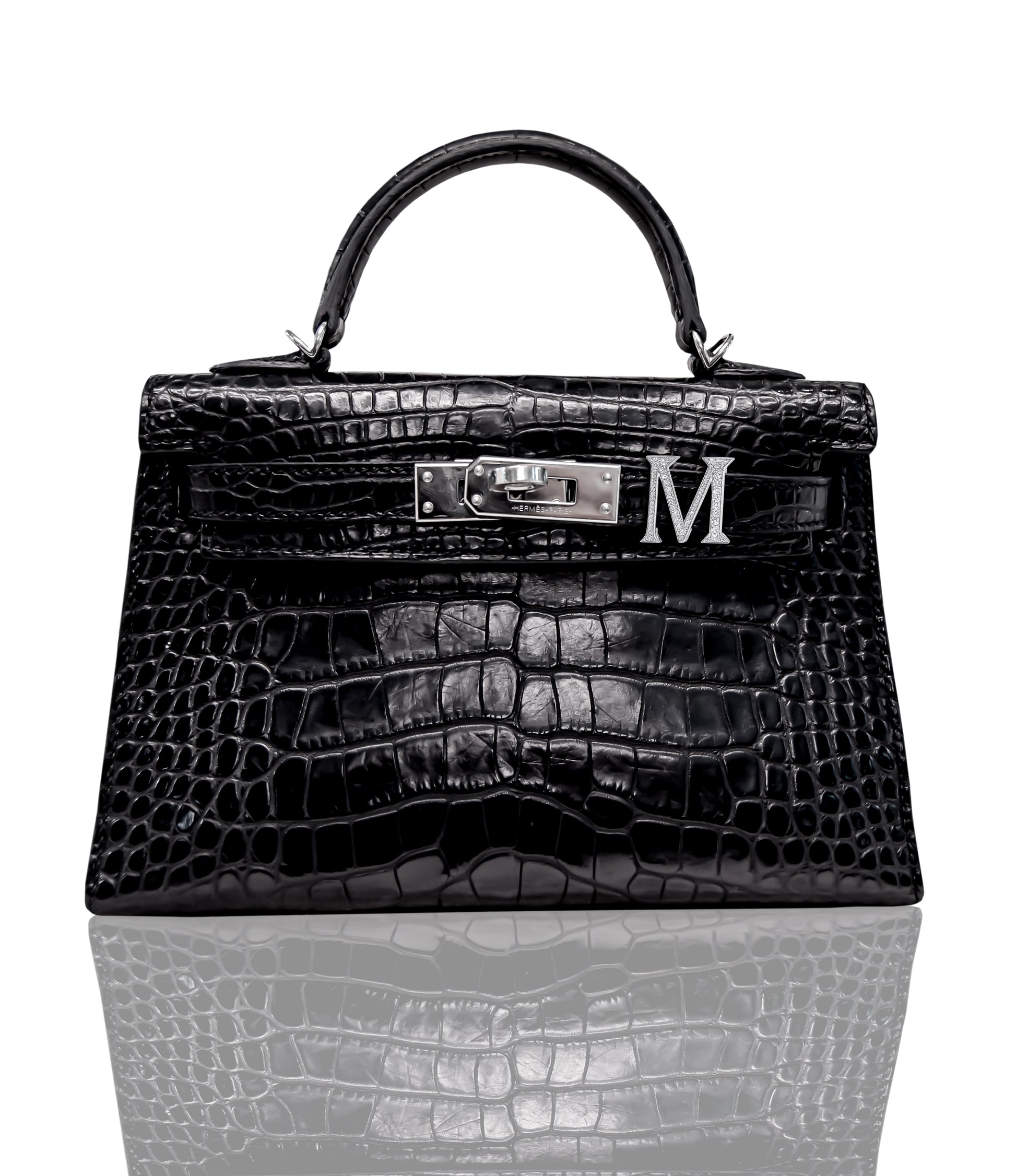 A black crocodile patterned handbag with a silver 'M' initial piece attached to the front, collection-preview.
