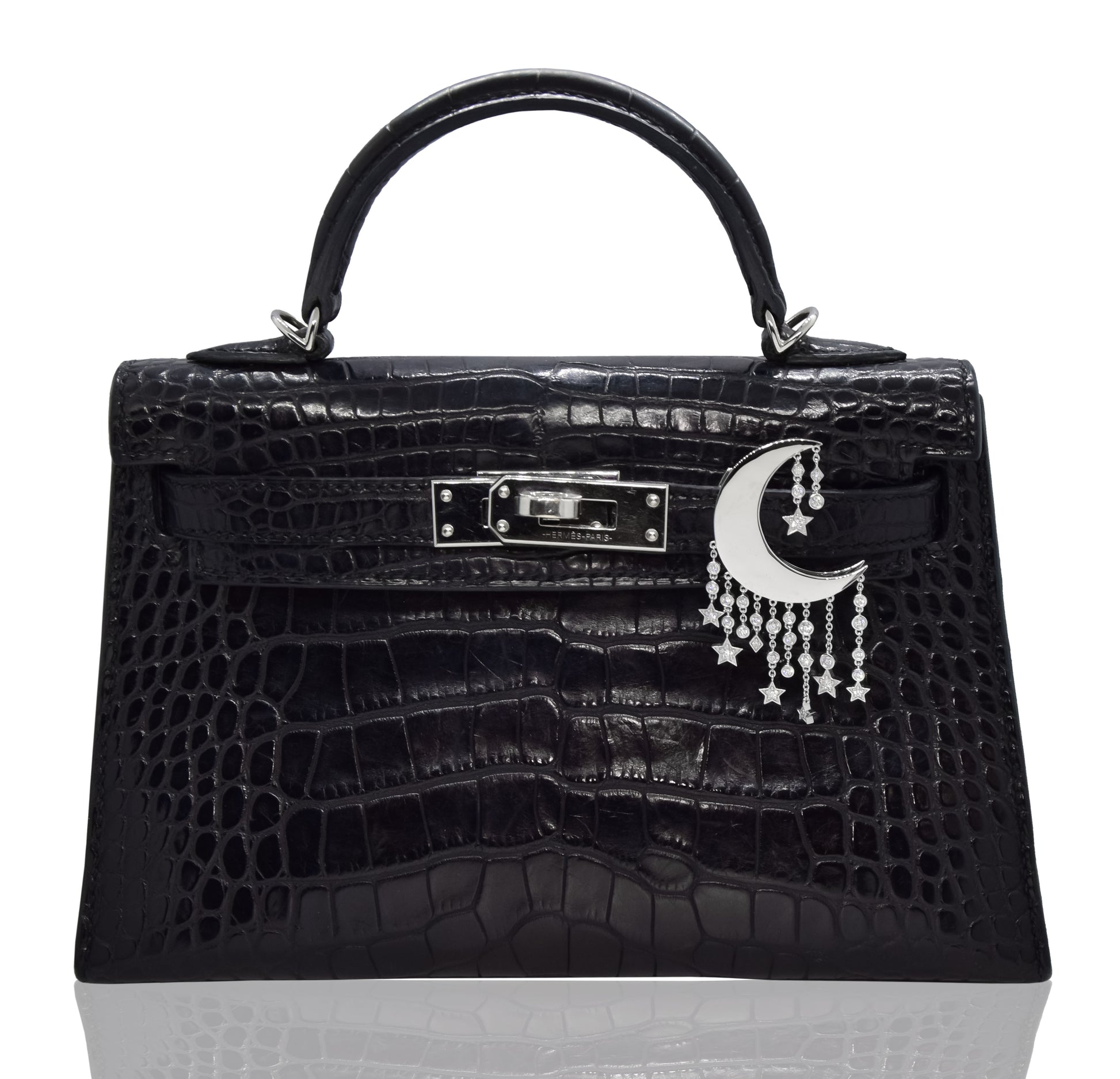 Black textured handbag with moon and star accessory on a white background, collection-preview
