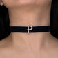 Black choker with a 'P' charm on a person's neck