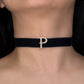 Black choker with a gold 'P' on a person's neck