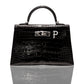 A black handbag with a crocodile pattern and a silver initial 'P' brooch attached to it, collection-preview.