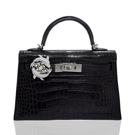 Black crocodile skin handbag with silver hardware on a white background, collection-preview