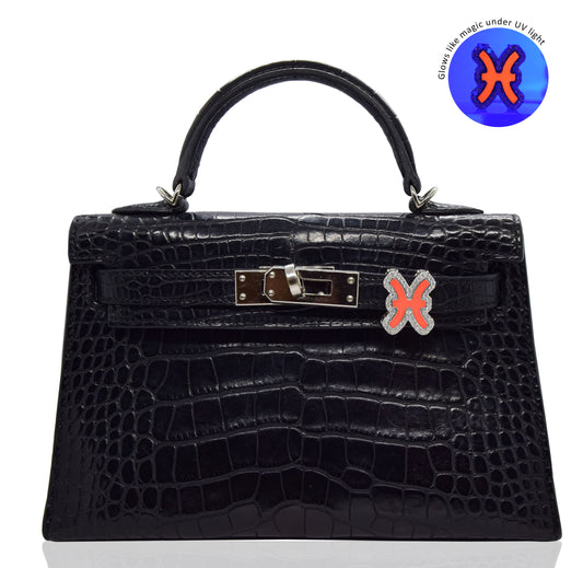 Black crocodile-patterned handbag with a distinctive clasp on a white background, collection-preview