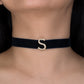 Navy blue choker with a gold 'S' on a person's neck