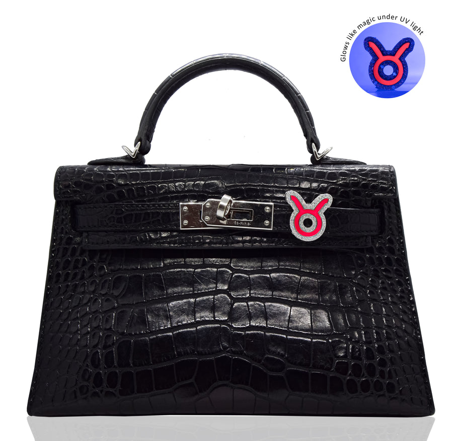 Black crocodile skin handbag with a distinctive clasp on a white background, collection-preview