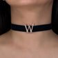 Black choker with a decorative 'W' on a person's neck
