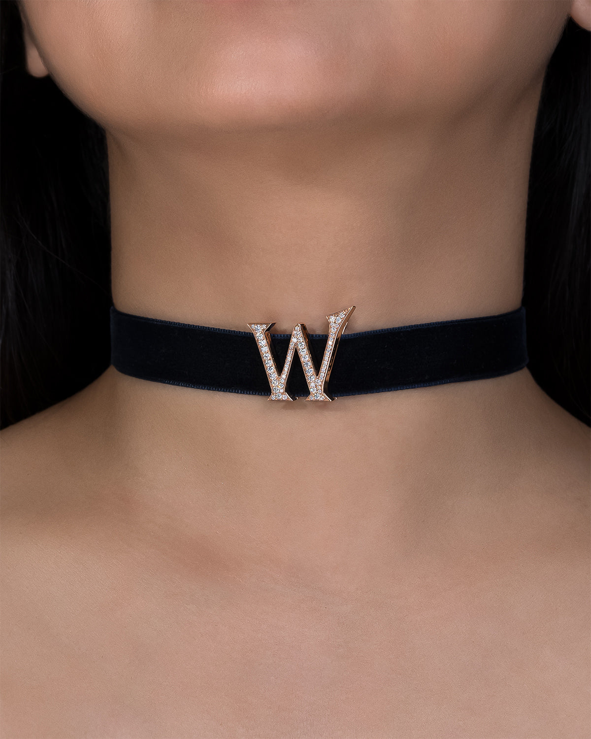 Black choker with a decorative 'W' on a person's neck