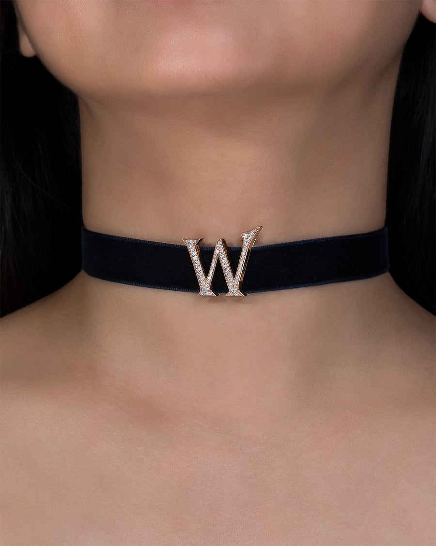 Black choker with a decorative 'W' on a person's neck
