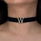 Black choker with a decorative 'W' on a person's neck