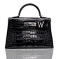 A black handbag with a crocodile pattern featuring a brooch with a 'W' initial, collection-preview.