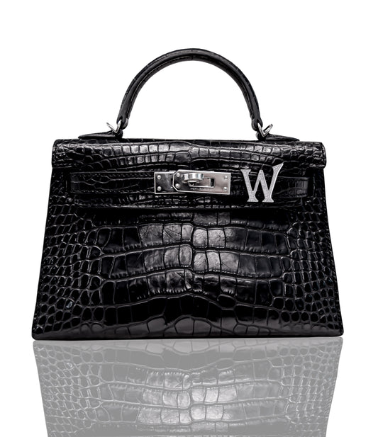 A black handbag with a crocodile pattern featuring a brooch with a 'W' initial, collection-preview.