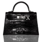 A black handbag with a crocodile pattern and a diamond-encrusted 'X' letter on the front, collection-preview.